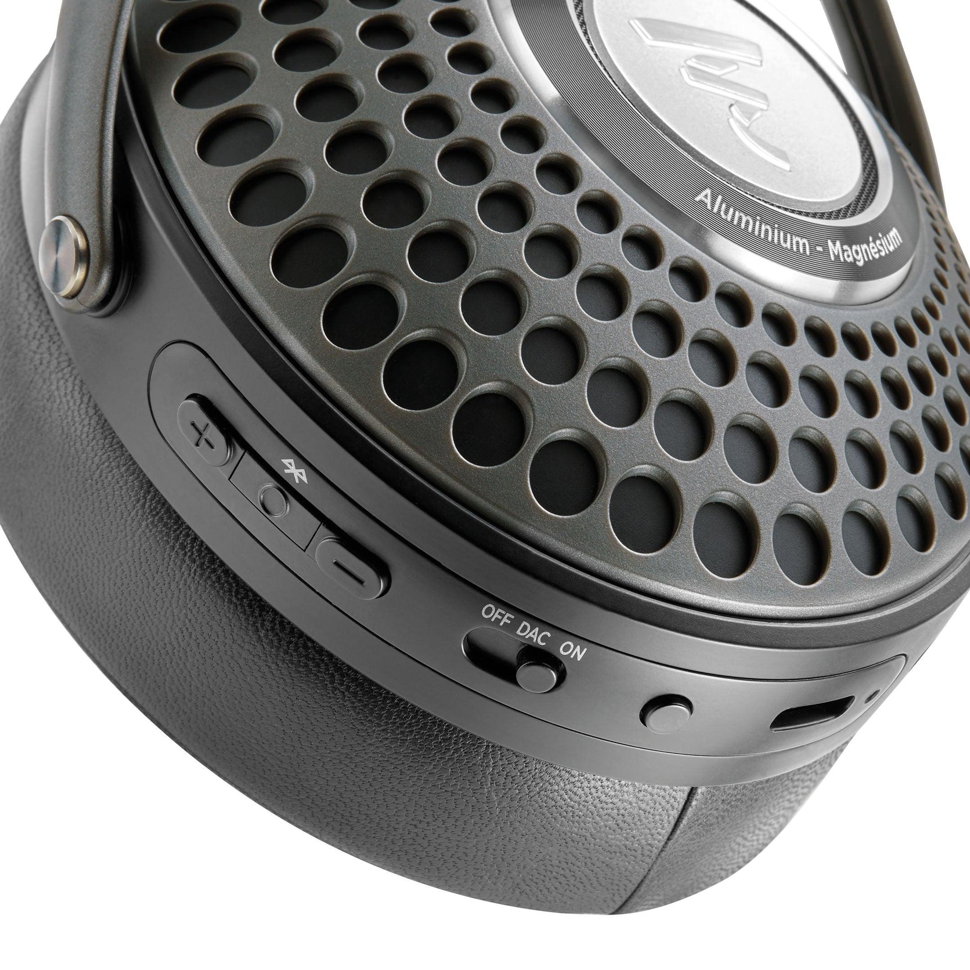 Close-up of a Focal Bathys black over-ear headphone earcup with perforated metal, control buttons, OFF/DAC/ON switch, USB port, and Aluminium - Magnesium labeled on these Focal active noise-canceling headphones.