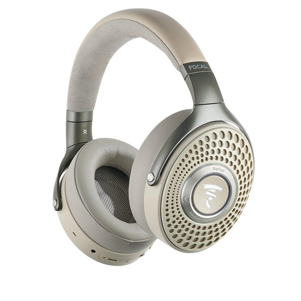 Focal Bathys over-ear wireless headphones in beige and silver feature a perforated outer earcup, padded headband, active noise-canceling tech, and the Focal brand name displayed on the headband.