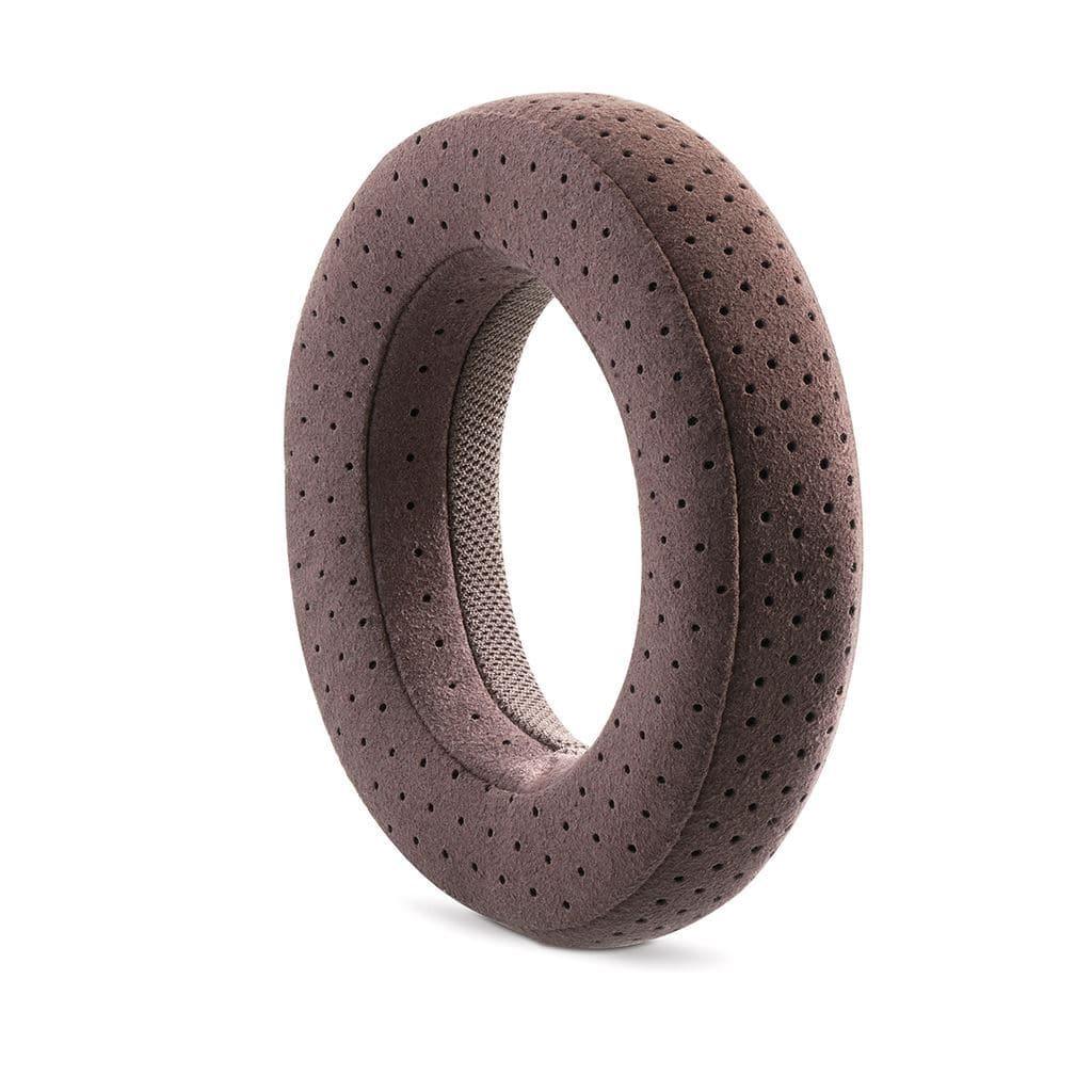 The Focal Clear Mg headphones by Focal feature plush, brown, donut-shaped ear pads with a perforated, breathable fabric design—evoking high-fidelity comfort—displayed upright on a white background.