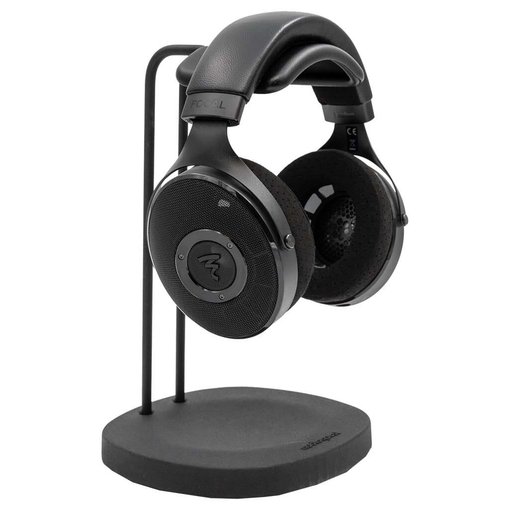 Focal Elex Headphones by Focal, featuring cushioned ear pads and a padded headband, rest on a sleek black stand. The Focal logo appears on the ear cups and base, emphasizing the brands dedication to premium sound quality.